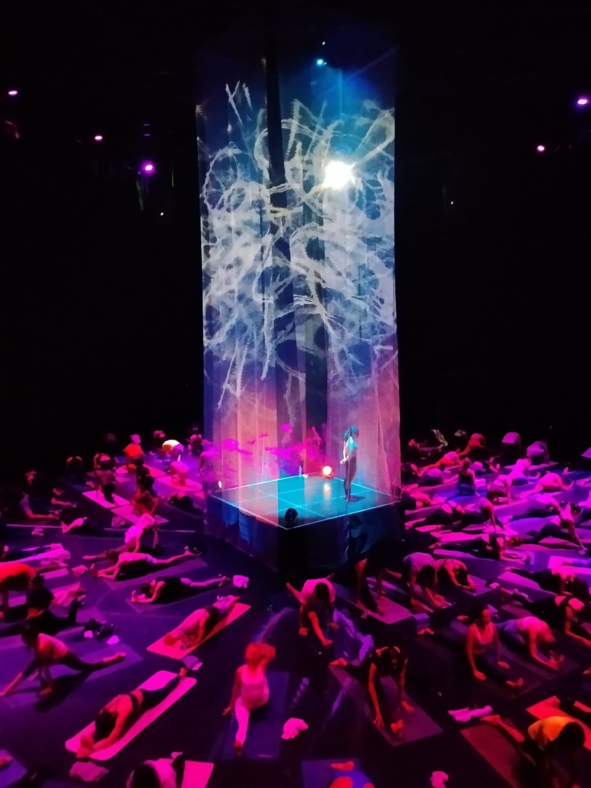 Columna de luz con visuales generativos rosa y público practicando yoga en el Conjunto Santander, Guadalajara